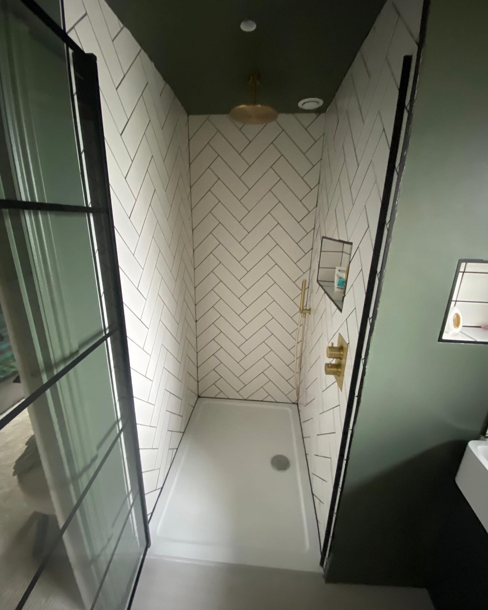 Shower with white herringbone tiles and brushed brass fittings